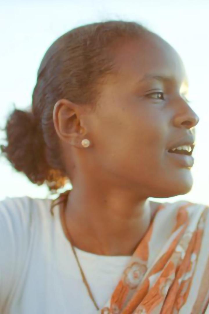 Eine junge Frau mit dunkler Haut und hochgesteckten Haaren schaut zur Seite.