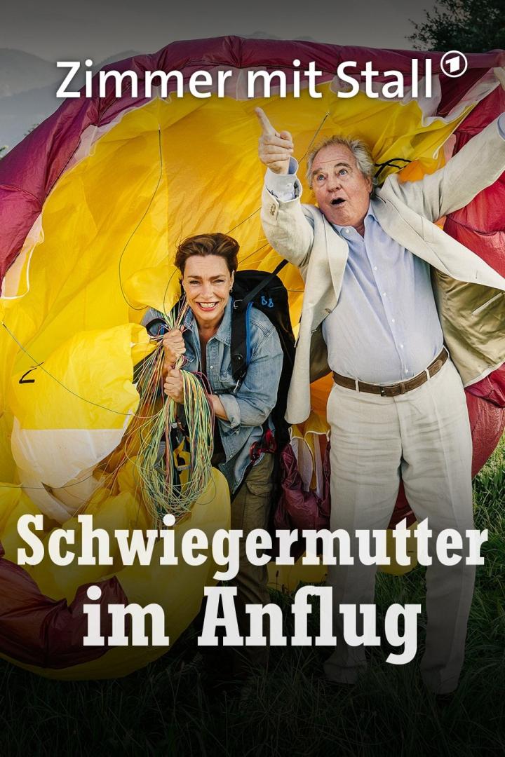 Das Filmplakat zu „Zimmer mit Stall – Schwiegermutter im Anflug“ zeigt zwei Personen vor einem Fallschirm.