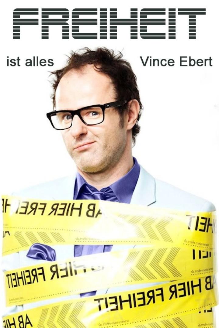 Vince Ebert, mit gelbem Band umwickelt, auf dem „Freiheit“ steht.