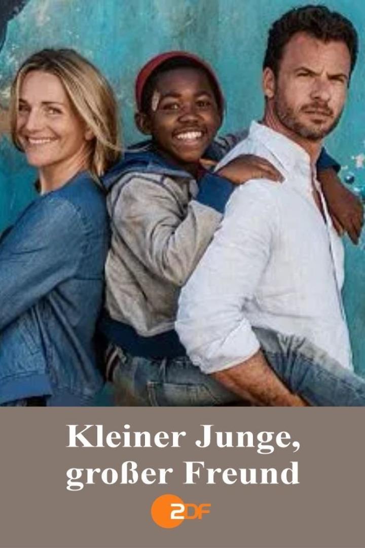 Ein lächelnder Junge steht zwischen einer Frau und einem Mann vor einer blauen Wand.
