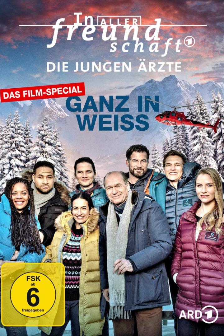 Das Filmplakat zu „In aller Freundschaft – Die jungen Ärzte: Ganz in Weiss“ mit dem Ensemble vor verschneiter Bergkulisse.