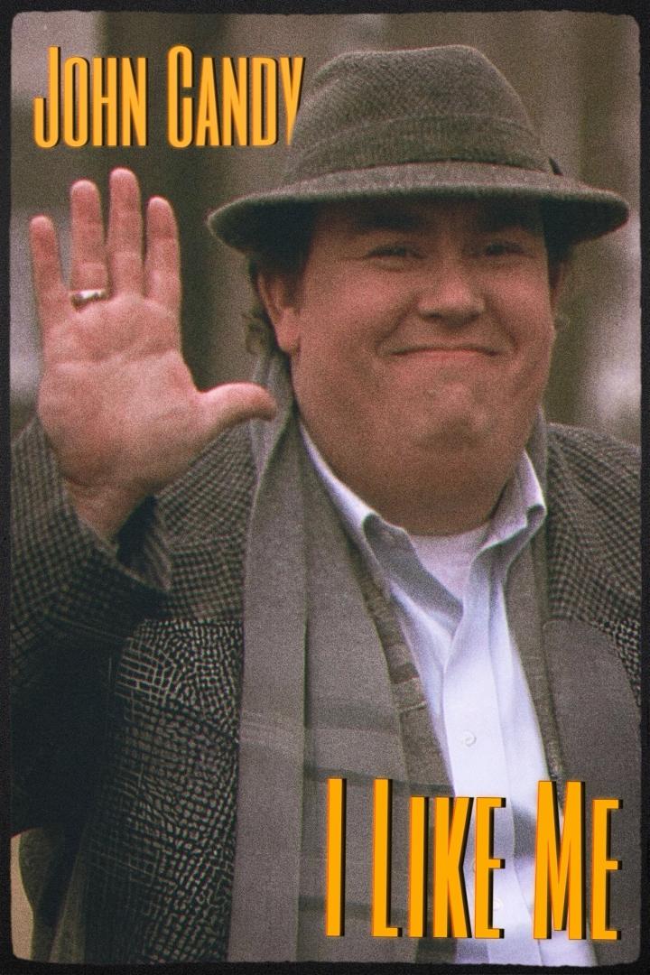 John Candy mit Hut und Schal winkt in die Kamera.