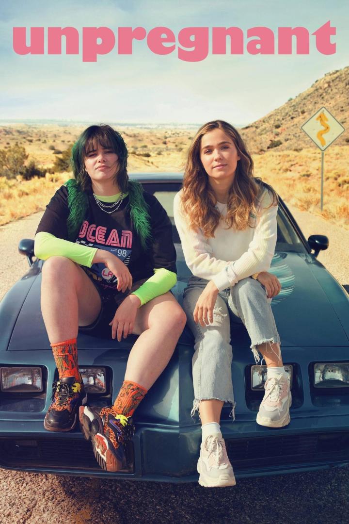 Zwei junge Frauen sitzen auf der Motorhaube eines Autos vor einer Wüstenlandschaft.