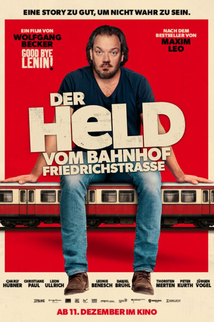 Charly Hübner sitzt auf einem Straßenbahnwagen
