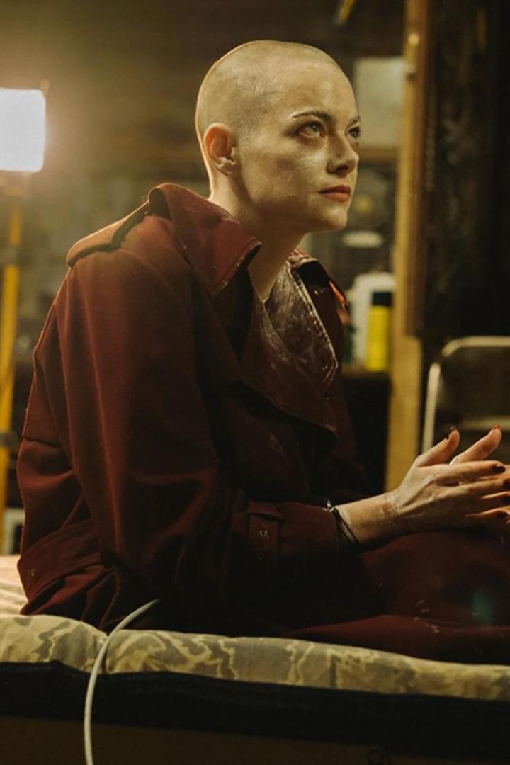 Kahlgeschorene Frau sitzt in Keller auf einer Liege