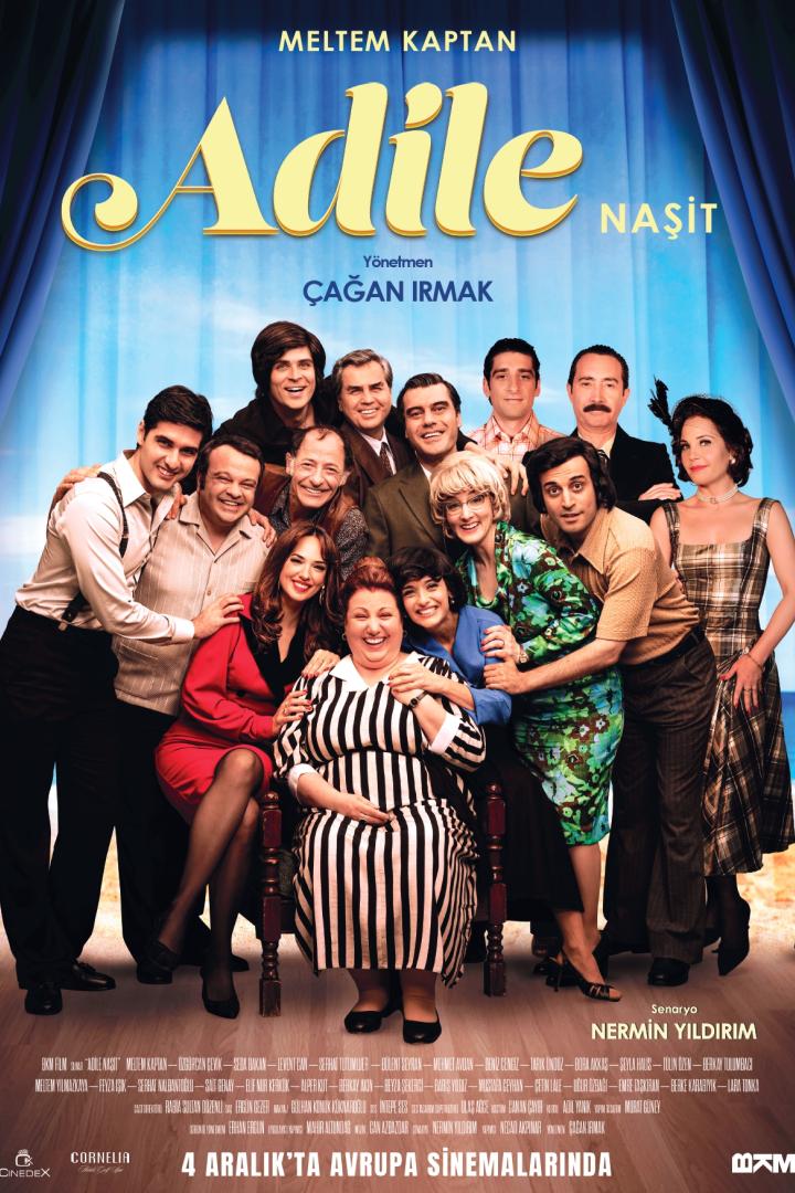 auf einer Theaterbühne ist ein ganzes Ensemble um eine sitzende ältere Frau versammelt