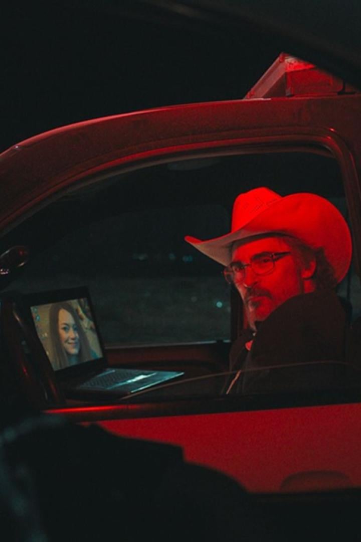 Joaquin Phoenix als Sheriff sitzt nachts in seinem Dienstwagen und wird durch einen Scheinwerfer in rotes Licht getaucht