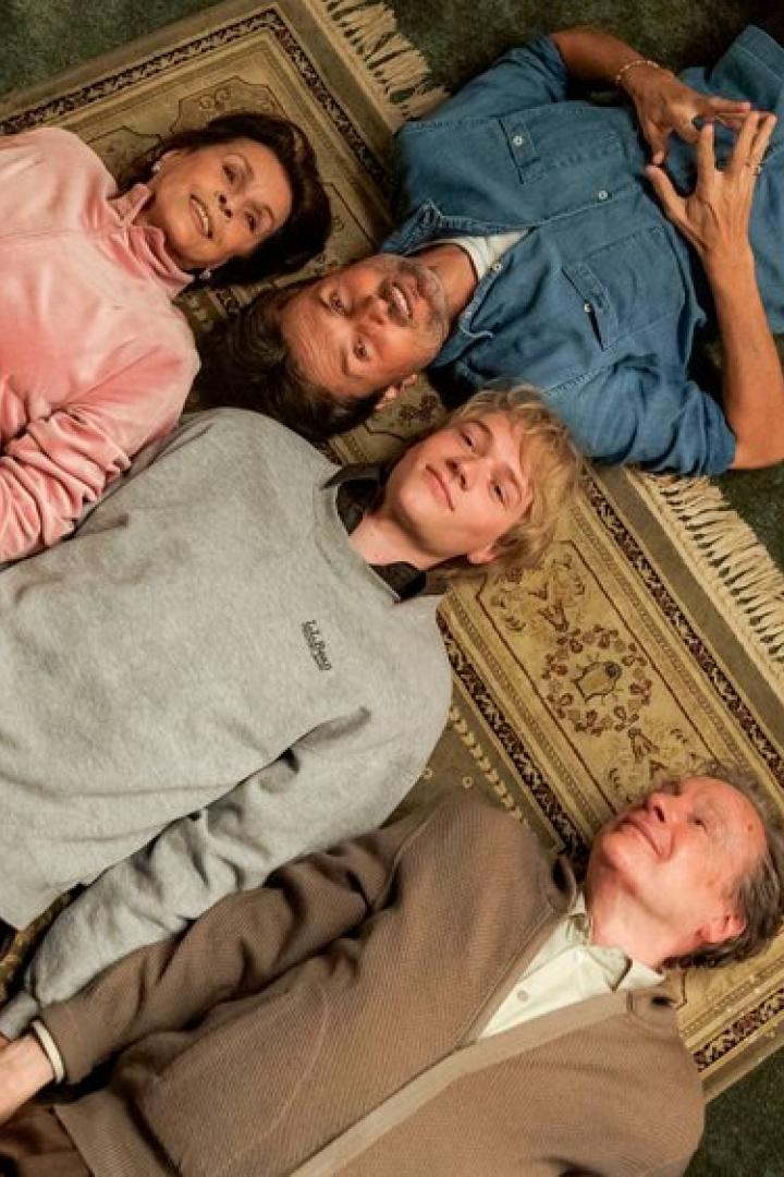 Großeltern und ihr Enkelsohn liegen auf dem Rücken auf einem Teppichboden