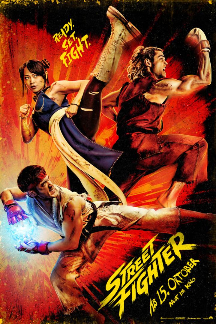 Actionreiches Street Fighter-Poster mit drei kämpfenden Figuren und gelbem Titel auf rotem Hintergrund.