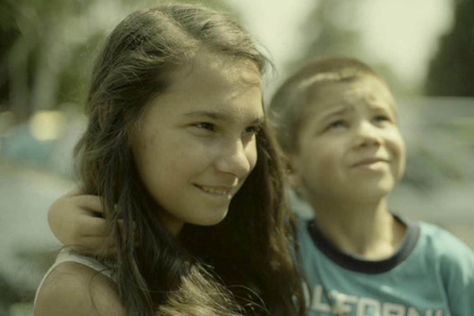 Ein Mädchen und ein Junge umarmen sich und schauen nach oben.