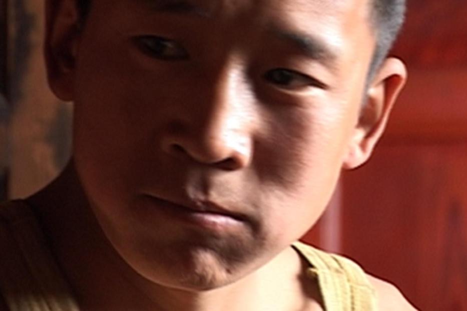 Ein junger Mann mit dunklen Haaren und einem ernsten Gesichtsausdruck.