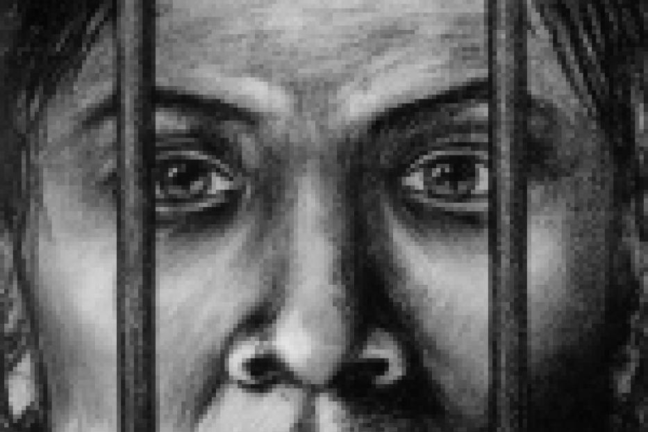 Das Gesicht einer Person hinter Gittern, mit einem besorgten Ausdruck.