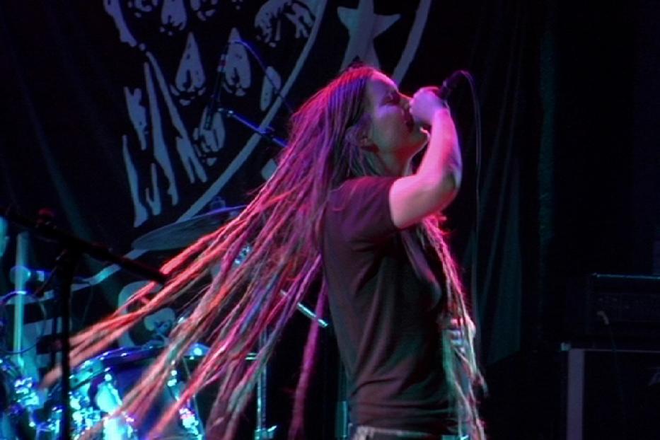 Eine Sängerin mit Dreadlocks tritt auf einer Bühne vor einem Schlagzeuger auf.