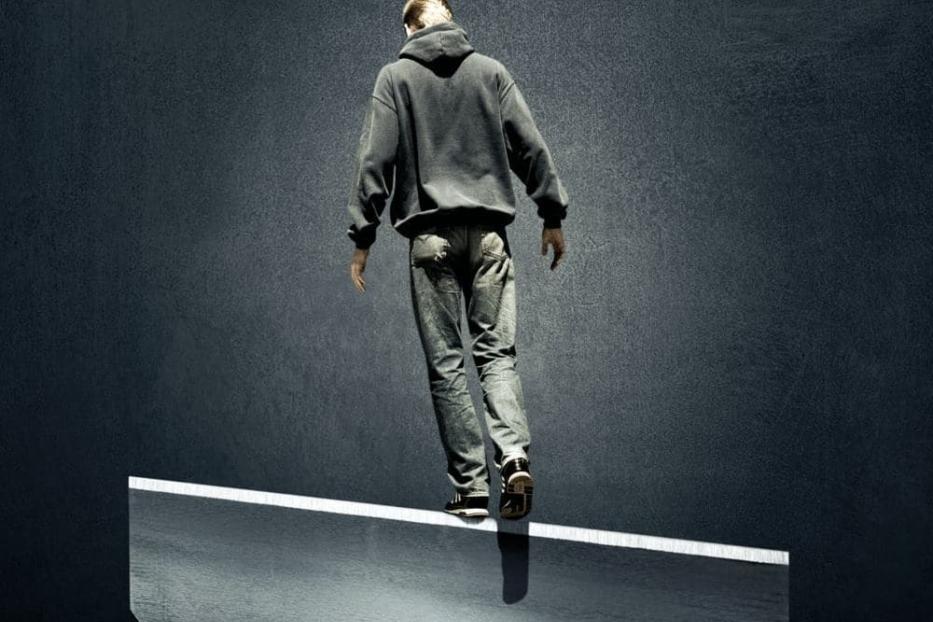 Ein Mann balanciert auf der Klinge einer Rasierklinge; im Hintergrund der Titel „Self Medicated“.