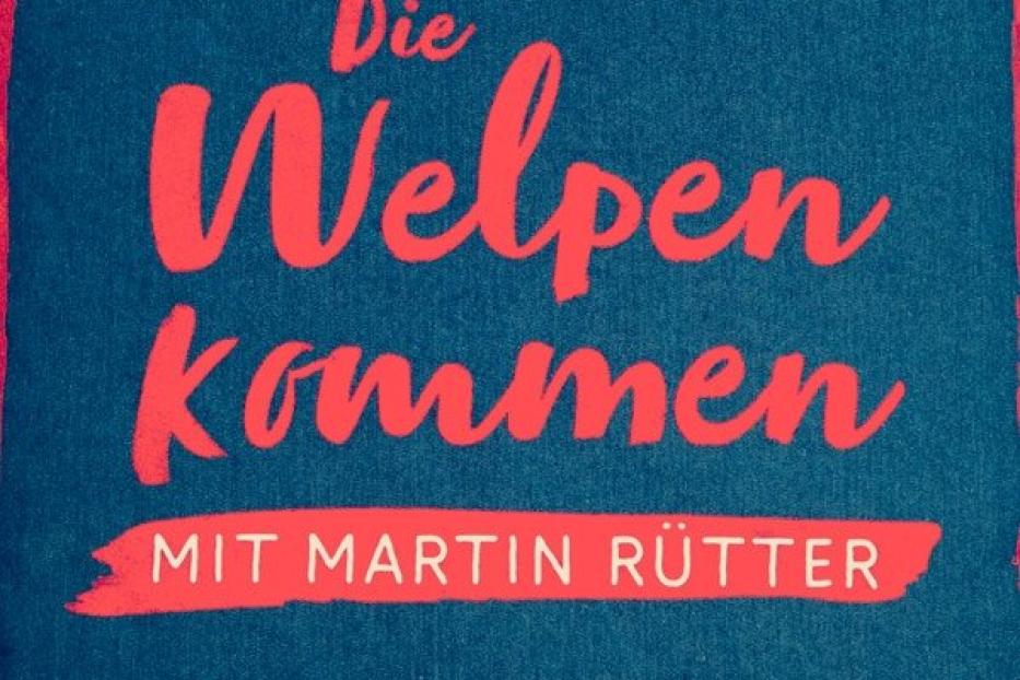 Ein Kissen mit der Aufschrift „Die Welpen kommen – mit Martin Rütter“.