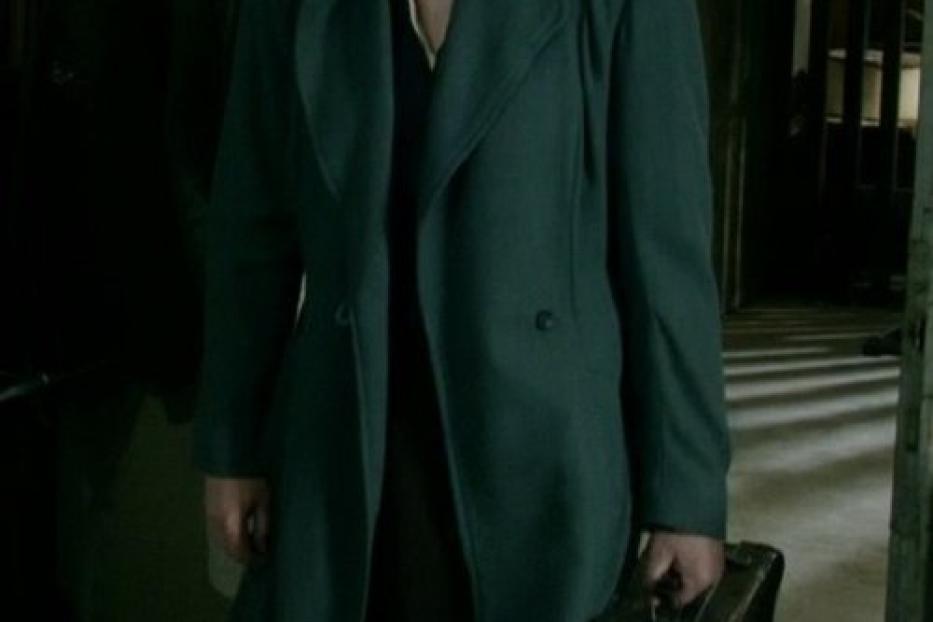 Eine Frau mit Mantel und Koffer, möglicherweise auf der Flucht.