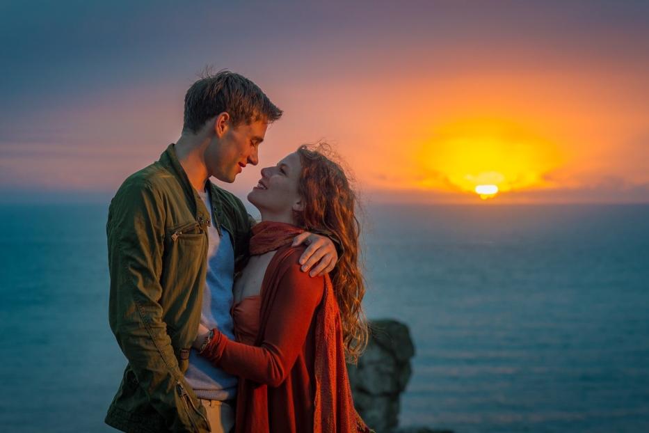 Ein Paar umarmt sich vor einem Sonnenuntergang am Meer.