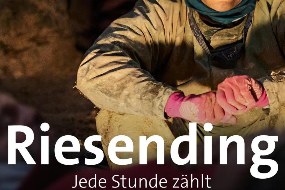 Ein verschmutzter junger Mann mit pinkfarbenen Handschuhen blickt in die Kamera.