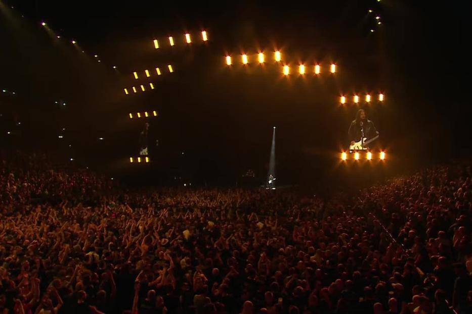 Ein Konzert mit einer Band auf der Bühne vor einem großen Publikum.