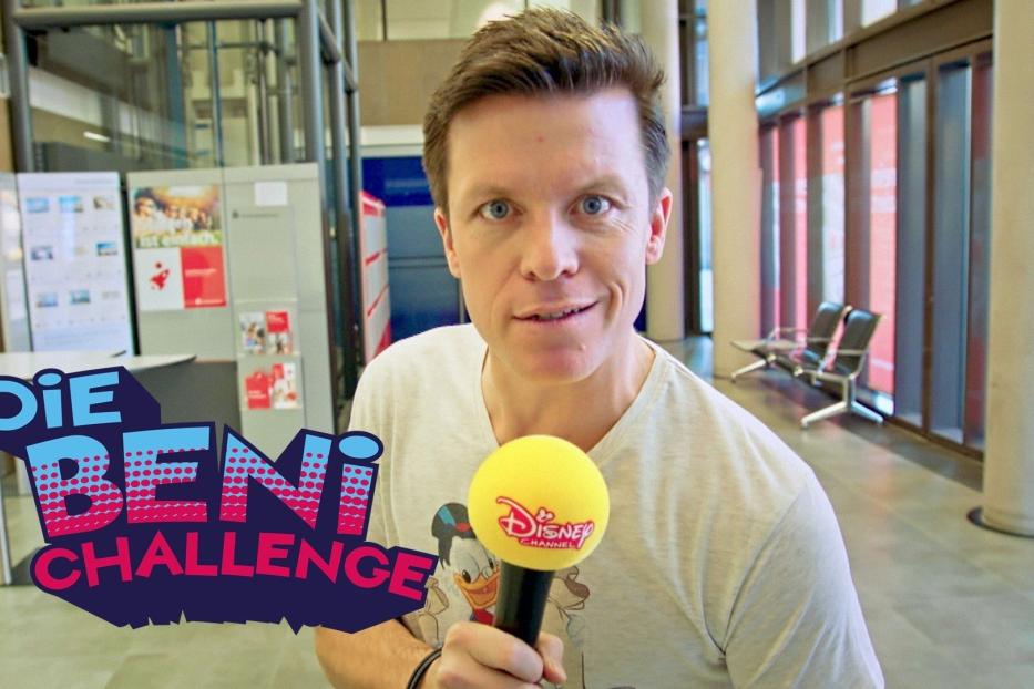 Ein Mann hält ein Mikrofon des Disney Channels in der Hand, im Hintergrund steht „Die Beni Challenge“.