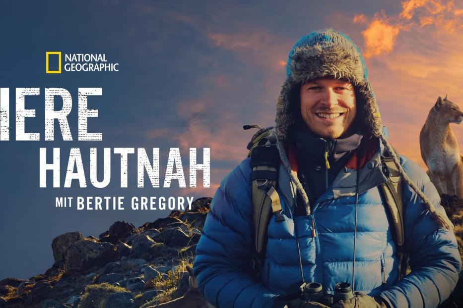 Bertie Gregory vor dem Hintergrund der National Geographic-Serie „Tiere hautnah“ mit einem Puma.