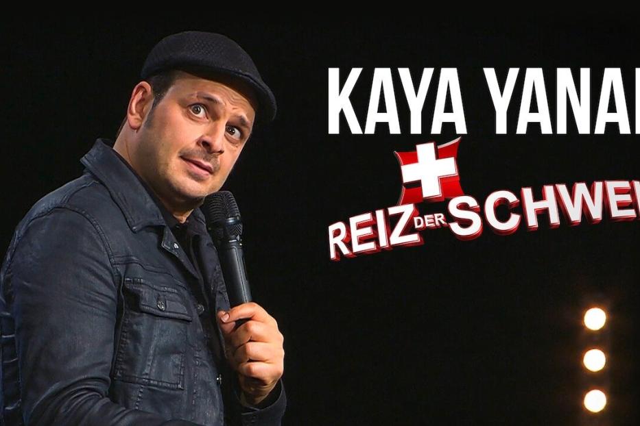 Kaya Yanar auf der Bühne mit dem Titel „Reiz der Schweiz“ im Hintergrund.