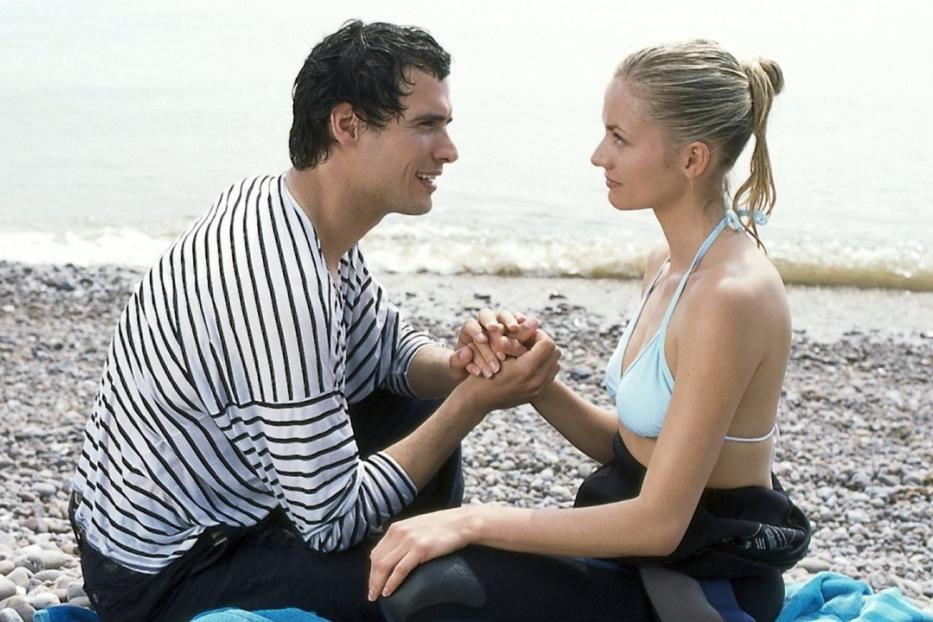 Ein Paar sitzt am Strand und hält Händchen.