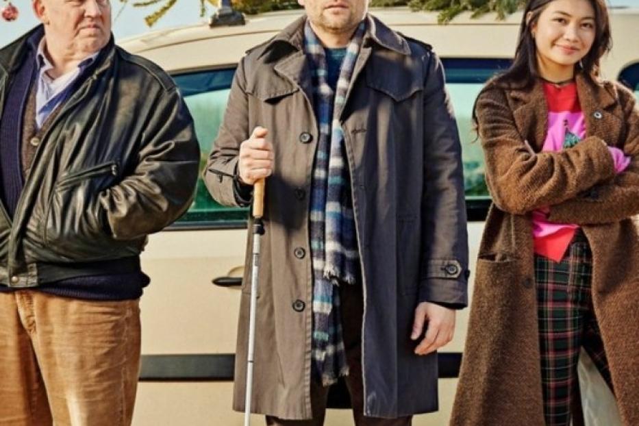 Drei Personen stehen vor einem Taxi mit einem Weihnachtsbaum auf dem Dach.