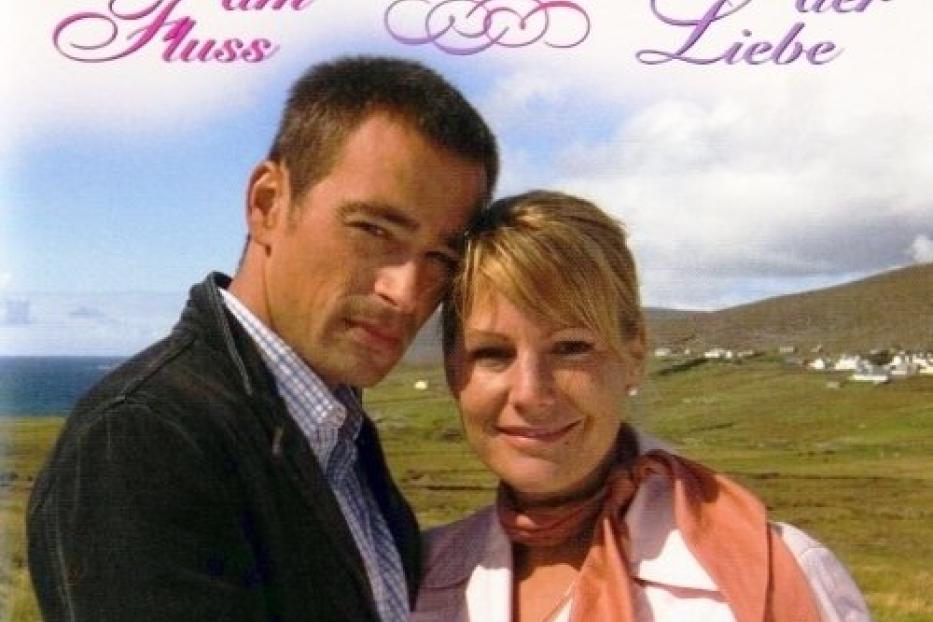 Das Cover des Rosamunde Pilcher Films „Wiedersehen am Fluss – Sommer der Liebe“ mit einem Paar vor einer Landschaft.