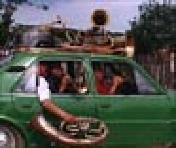 Ein grünes Auto ist mit Musikinstrumenten auf dem Dach beladen.