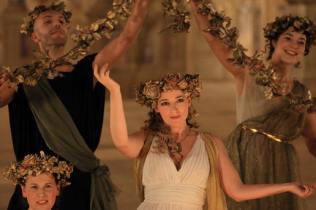 Mehrere Personen in Kostümen und mit Blumenkränzen posieren für ein Foto.