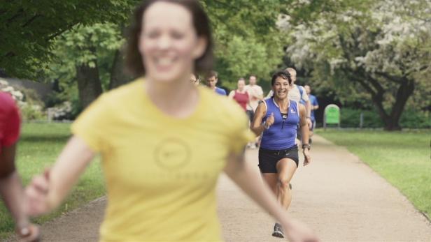 Eine Gruppe von Menschen joggt auf einem Weg in einem Park.