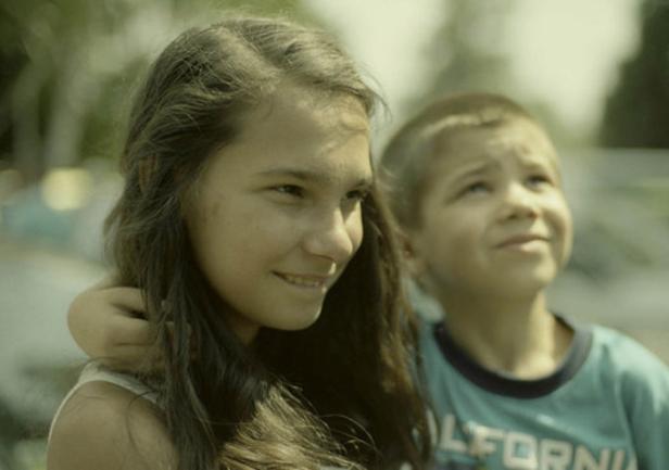 Ein Mädchen und ein Junge umarmen sich und schauen nach oben.