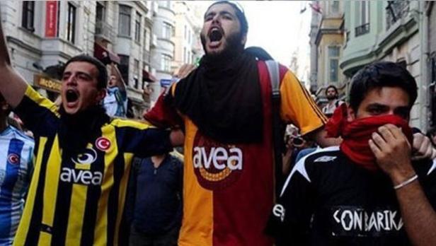 Eine Gruppe junger Männer demonstriert in Trikots verschiedener Fußballvereine auf einer Straße.