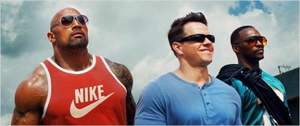 Dwayne Johnson, Mark Wahlberg und Anthony Mackie stehen zusammen vor einem bewölkten Himmel.