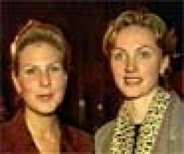 Zwei blonde Frauen stehen nebeneinander und lächeln.