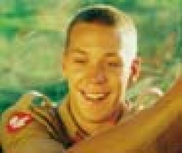 Ein junger Mann in Uniform lächelt in die Kamera.