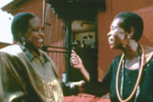 Zwei Frauen unterhalten sich lachend vor einem Haus.