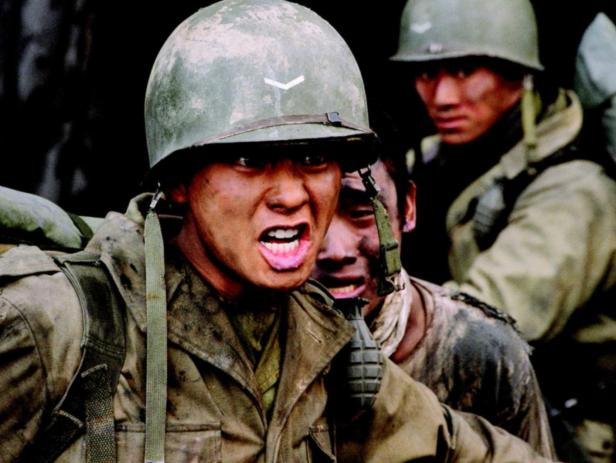 Ein Soldat mit schmutzigem Gesicht schreit, während er mit anderen Soldaten im Krieg kämpft.