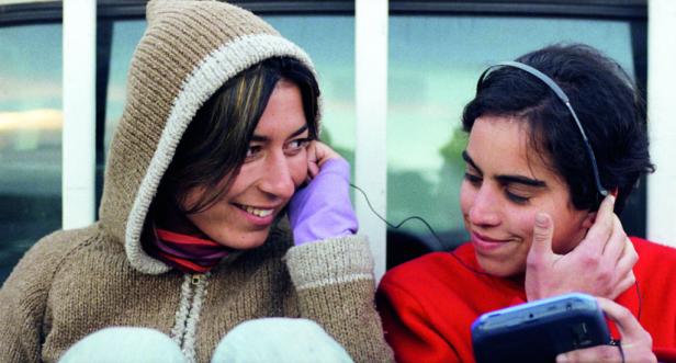 Zwei junge Leute hören mit Kopfhörern Musik von einem tragbaren Abspielgerät.