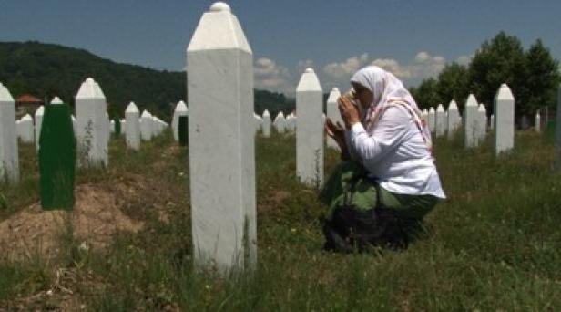 Eine muslimische Frau betet auf einem Friedhof mit weißen Grabsteinen.