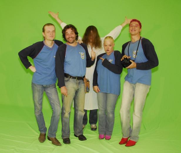 Eine Gruppe von fünf Personen posiert vor einem grünen Hintergrund.