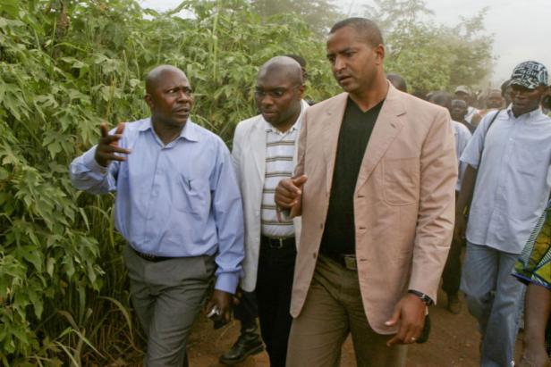 Drei Männer gehen an einem Feldweg entlang und unterhalten sich.