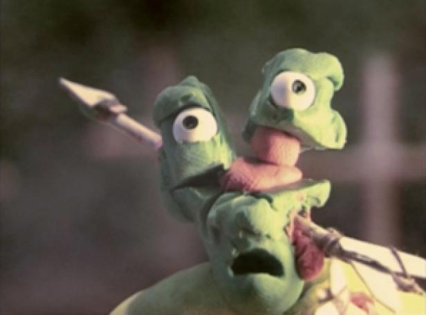 Eine grüne Knetfigur mit einem Pfeil im Kopf.