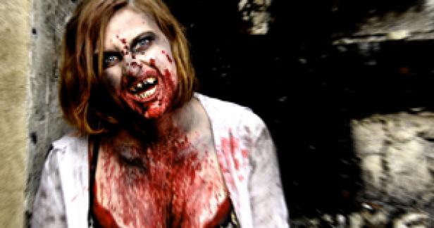 Eine Frau mit blutverschmiertem Gesicht und Zombie-Make-up steht vor einer dunklen Öffnung.