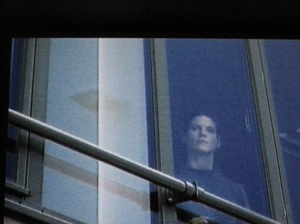 Eine Frau schaut aus einem Fenster in einem modernen Gebäude.