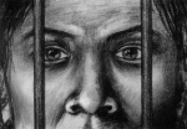 Das Gesicht einer Person hinter Gittern, mit einem besorgten Ausdruck.