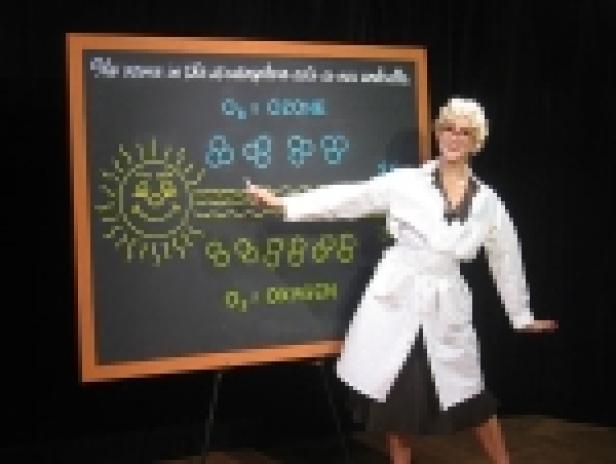 Eine Frau im Laborkittel erklärt die Ozonschicht vor einer Tafel.