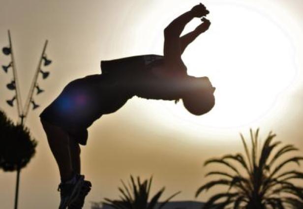 Die Silhouette eines Mannes, der vor dem Hintergrund der untergehenden Sonne einen Rückwärtssalto macht.