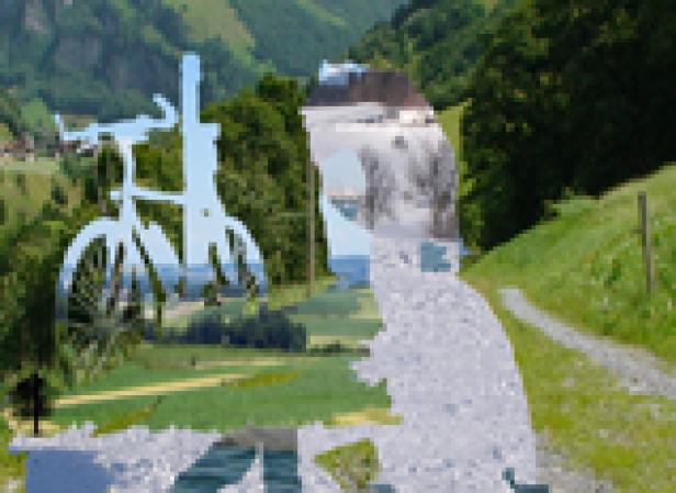 Eine silberne Fahrradskulptur steht vor einer grünen Landschaft.